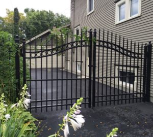 A black ornamental iron over arch estate gate near the side of a house