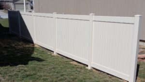 Four sections of a vinyl privacy fence near the side of a house