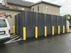 Mission Dispensary featuring dark gray PalmSHIELD louvered mechanical equipment screening with bright yellow traffic columns installed along the perimeter for protection