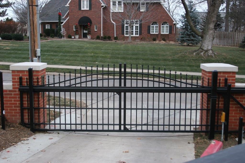 Residential ornamental cantilever estate gate between two brick pillars