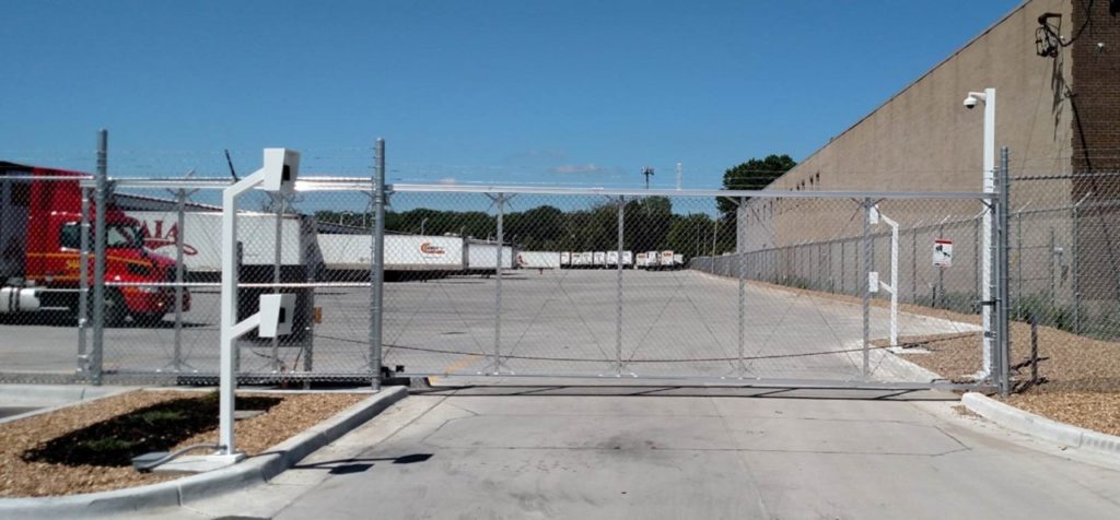 High security cantilever gate with barb wire, monitoring devices and gate access controls such as keypads on either side of the gate