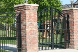 Double swing commercial swing gate, ornamental gate secured to brick columns