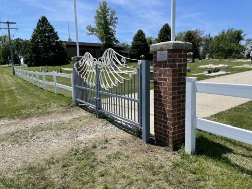 Ornamental swing gate with wing arches along the top. Attaches to brick columns. Brick columns have rod's going up with banner St Johns Cemetery